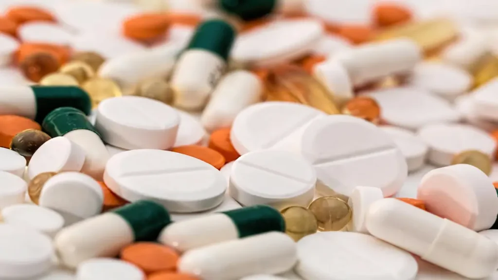 Close-up of assorted colorful pills and capsules spread across a surface.