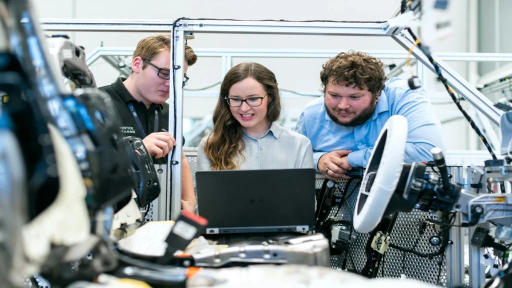 eam of engineers reviewing data on a laptop inside a vehicle testing setup