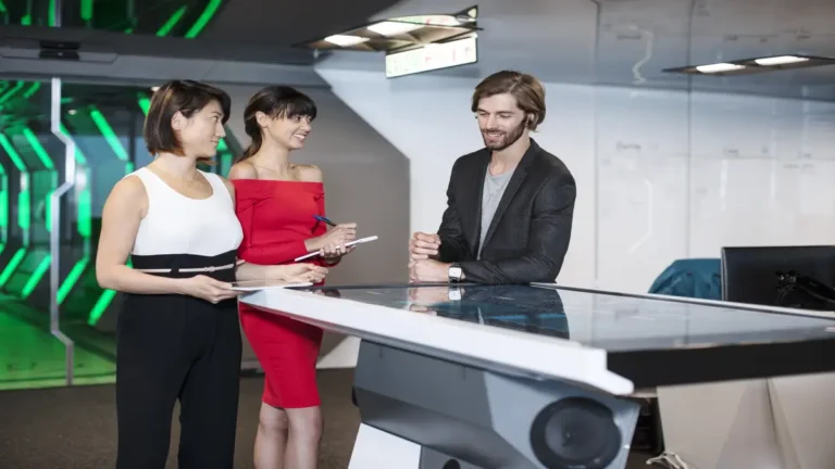 Tech startup team discussing innovation strategy around a smart digital table in a futuristic office environment