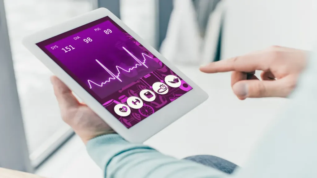 Man using a tablet displaying real-time heart rate data from a wearable health monitoring device