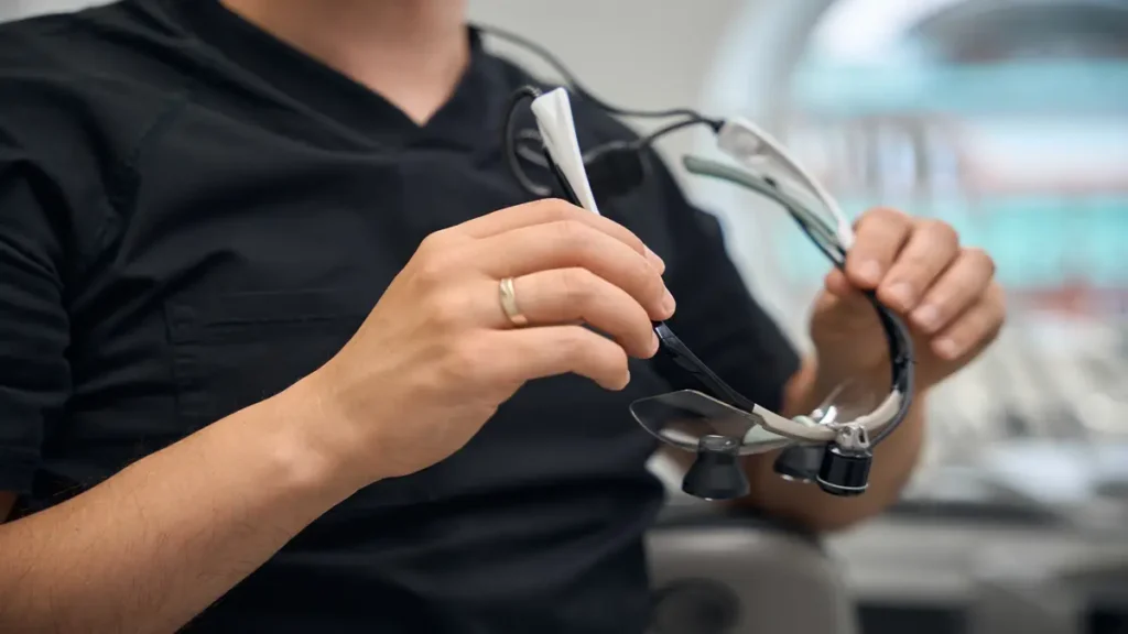 Close-up of hands holding modern smart glasses with medical lenses and tech attachments