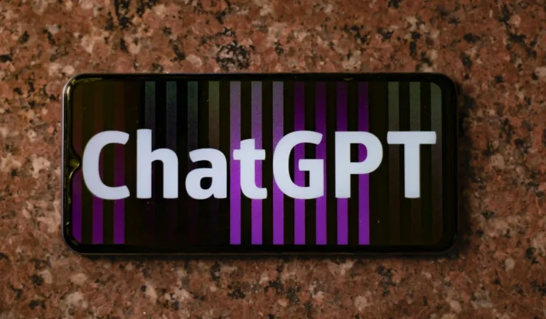AI Innovations - Smartphone screen displaying the word “ChatGPT” in bold white letters against a background of vertical purple and black stripes, placed on a granite surface