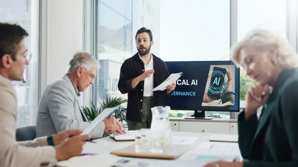 Business team in a modern office listening to a presenter discuss ethical AI, with a digital display showing AI graphics